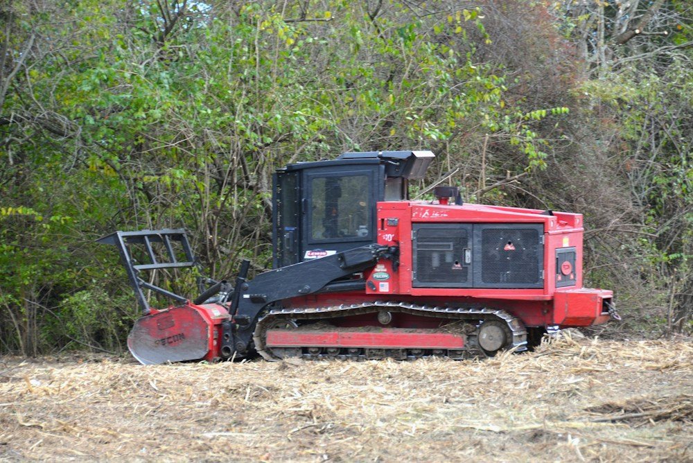 A forestry mulcher attachment on a skid steer clearing brush and saplings